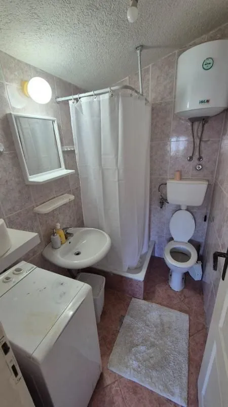 Bathroom equipped with a shower cabin, washbasin, toilet, and washing machine.