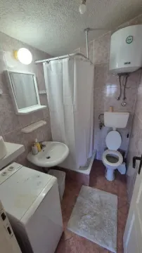 Bathroom equipped with a shower cabin, washbasin, toilet, and washing machine. - image 3