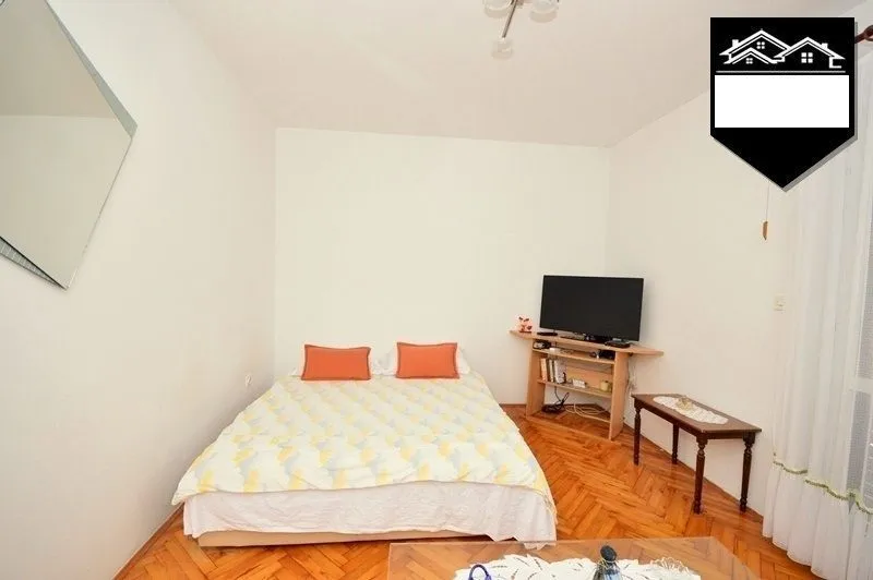 Furnished bedroom with a double bed and a television.