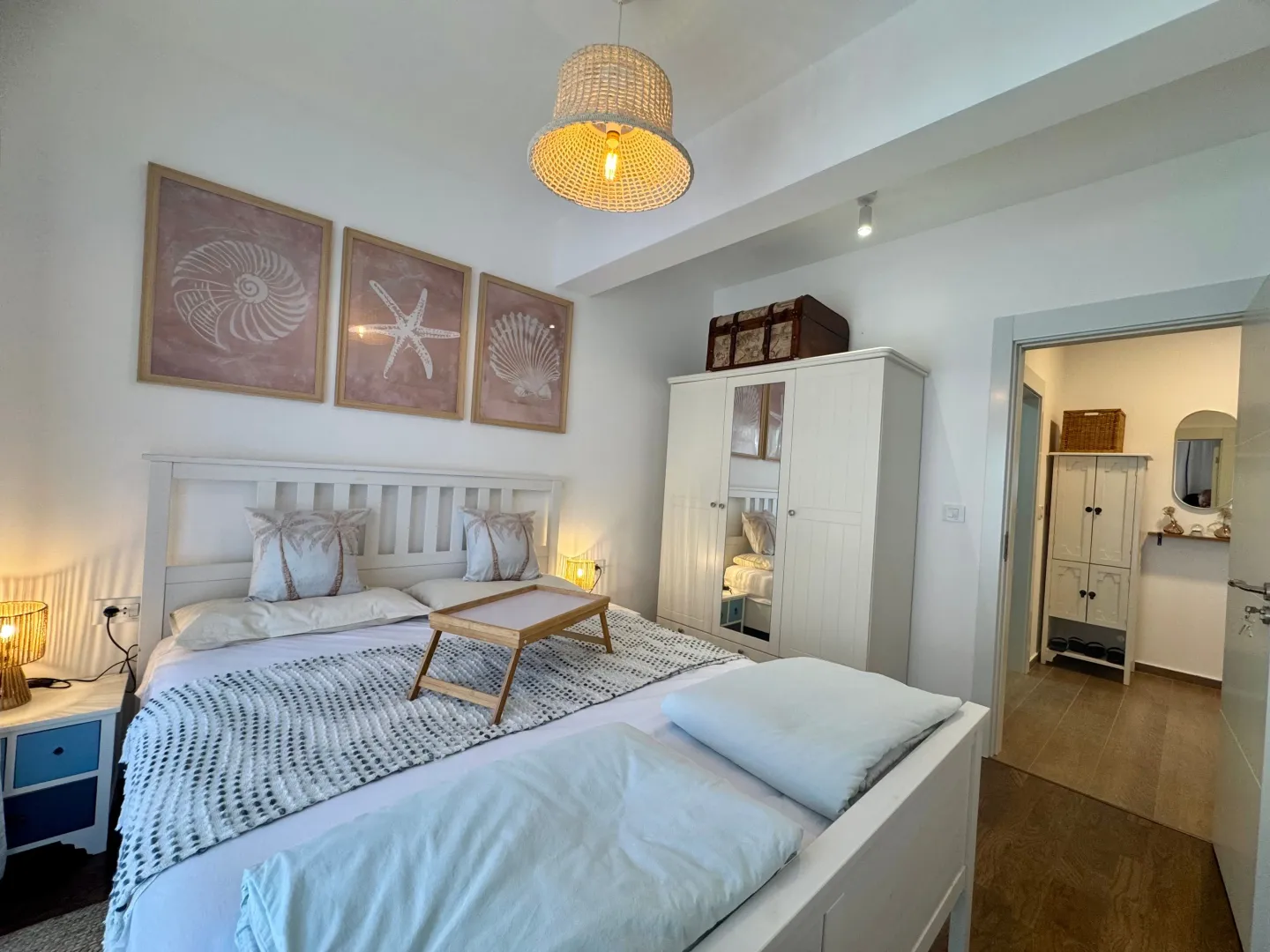 Bright and tidy bedroom with a white bed and decorative pictures on the wall.