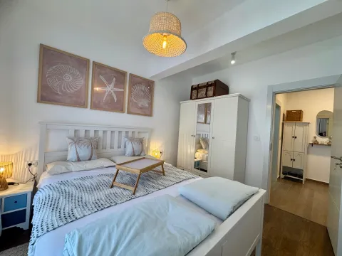 Bright and tidy bedroom with a white bed and decorative pictures on the wall. - image 9