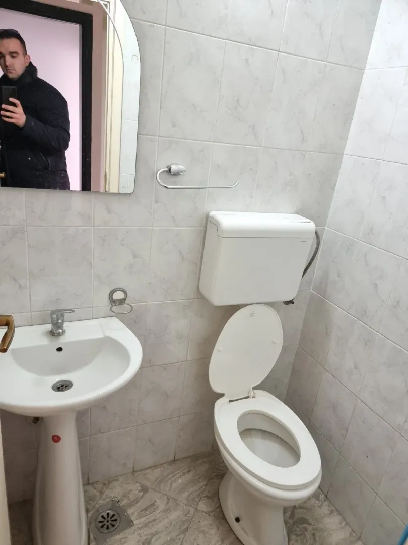 A small bathroom featuring a sink, mirror, and toilet.