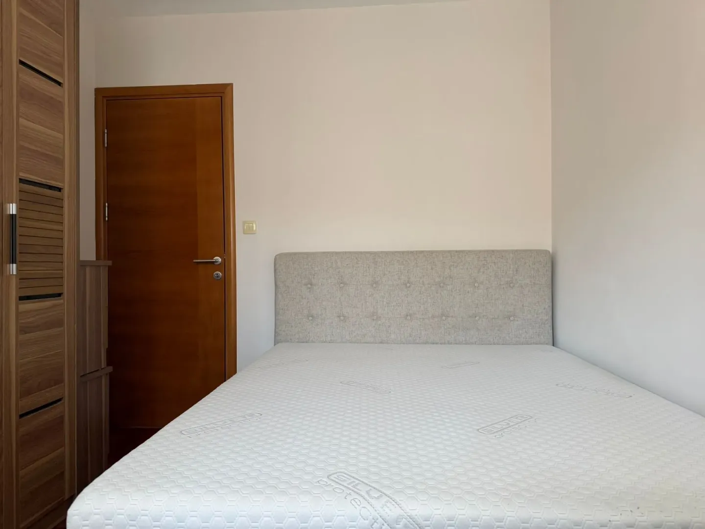 Small bedroom with a double bed, wardrobe, and wooden door.
