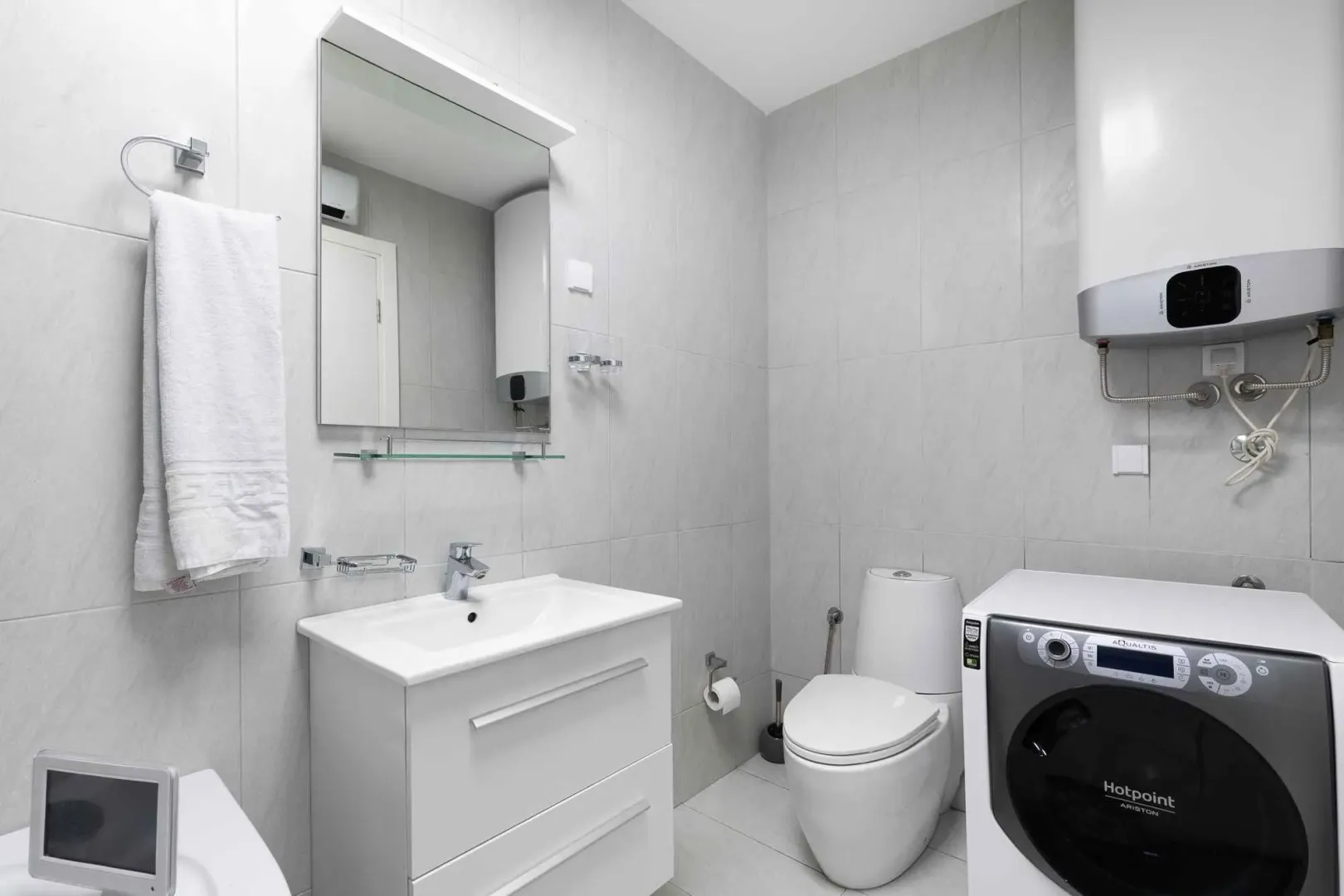 Modernly equipped bathroom with white sanitary ware, sink, and washing machine.