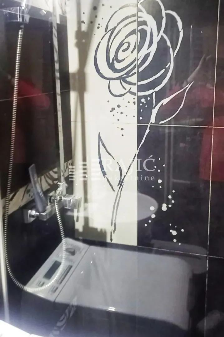 Bathroom with a shower cabin, decorative tiles, and a washing machine.