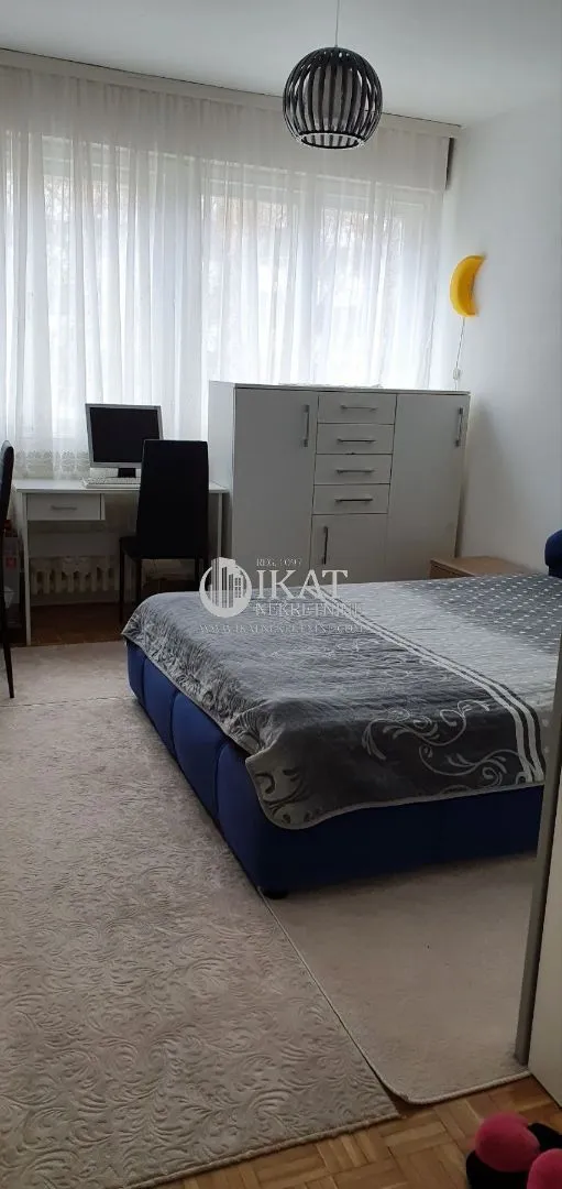 Furnished bedroom with a double bed, desk, and wardrobe.