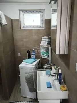 Manje kupatilo sa umivaonikom, veš mašinom i pločicama braon boje. - image 11