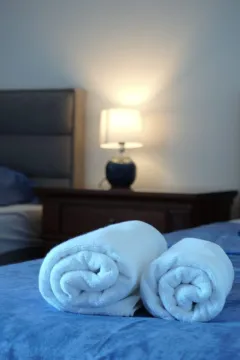 Pogled na krevet sa uredno složenim peškirima i noćnom lampom u spavaćoj sobi. - image 8