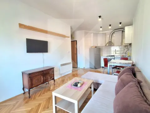 Dnevna soba sa garniturom, TV-om i trpezarijskim dijelom sa kuhinjom u pozadini. - image 2