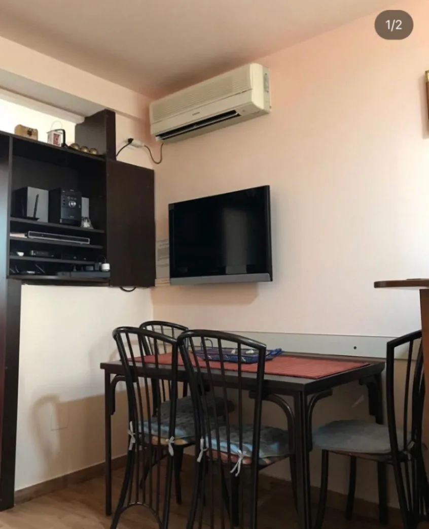 Living room with a dining table, television, and air conditioning unit.