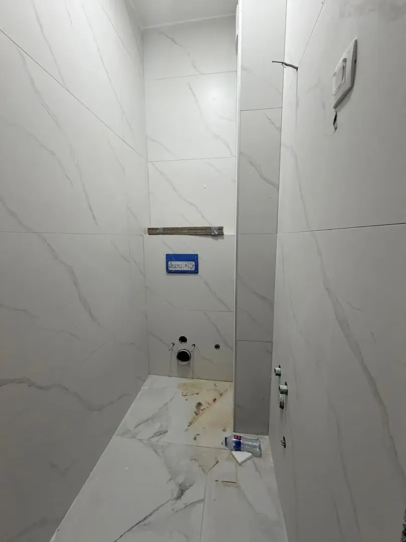 Kupatilo u fazi renoviranja obloženo mermernim pločicama sa pripremljenim priključcima za sanitarije.