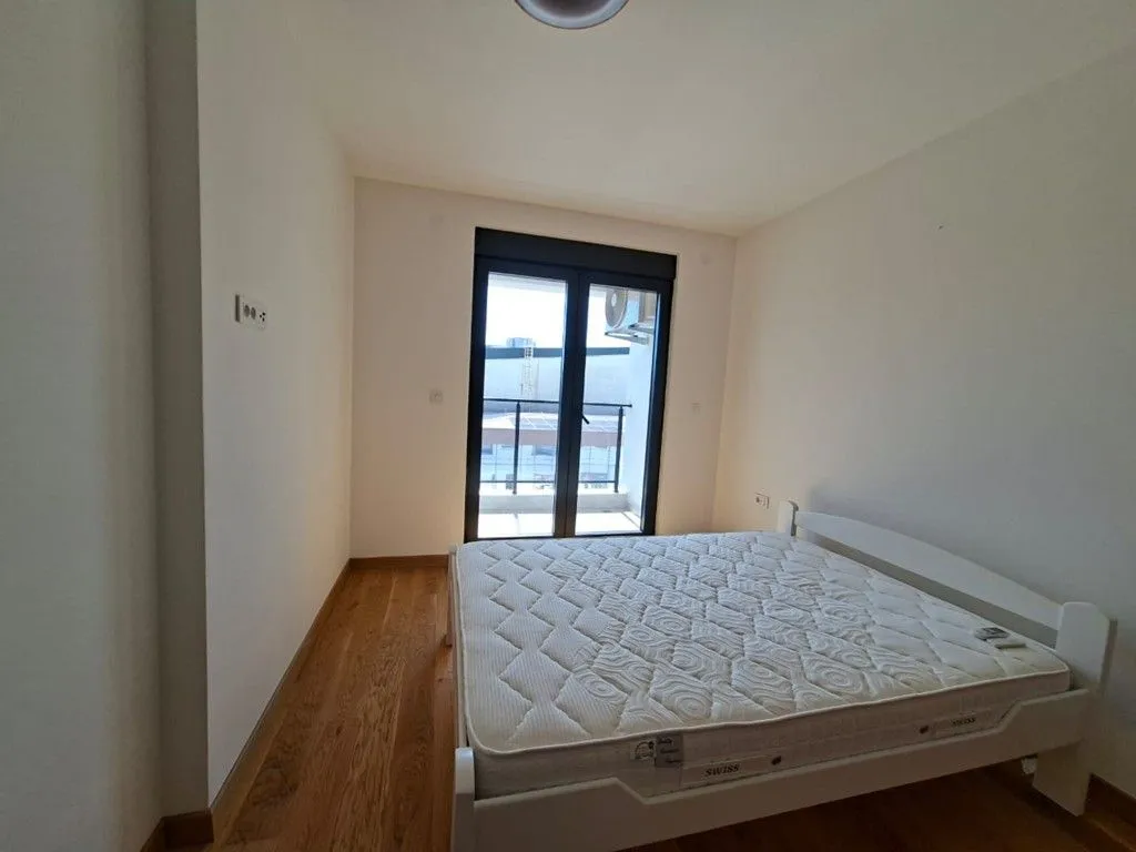 Svjetla spavaća soba sa bračnim krevetom i izlazom na terasu.