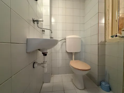 Manje kupatilo obloženo belim pločicama sa umivaonikom i wc šoljom. - image 8