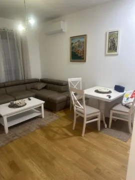 Living room with a sofa, dining table, and paintings on the wall. - image 3