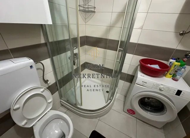 Kupatilo sa tuš kabinom, WC šoljom i veš mašinom.