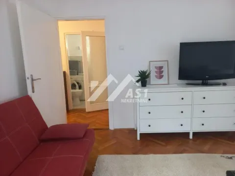 Dnevni boravak sa crvenim kaučem, komodom i televizorom. - image 3