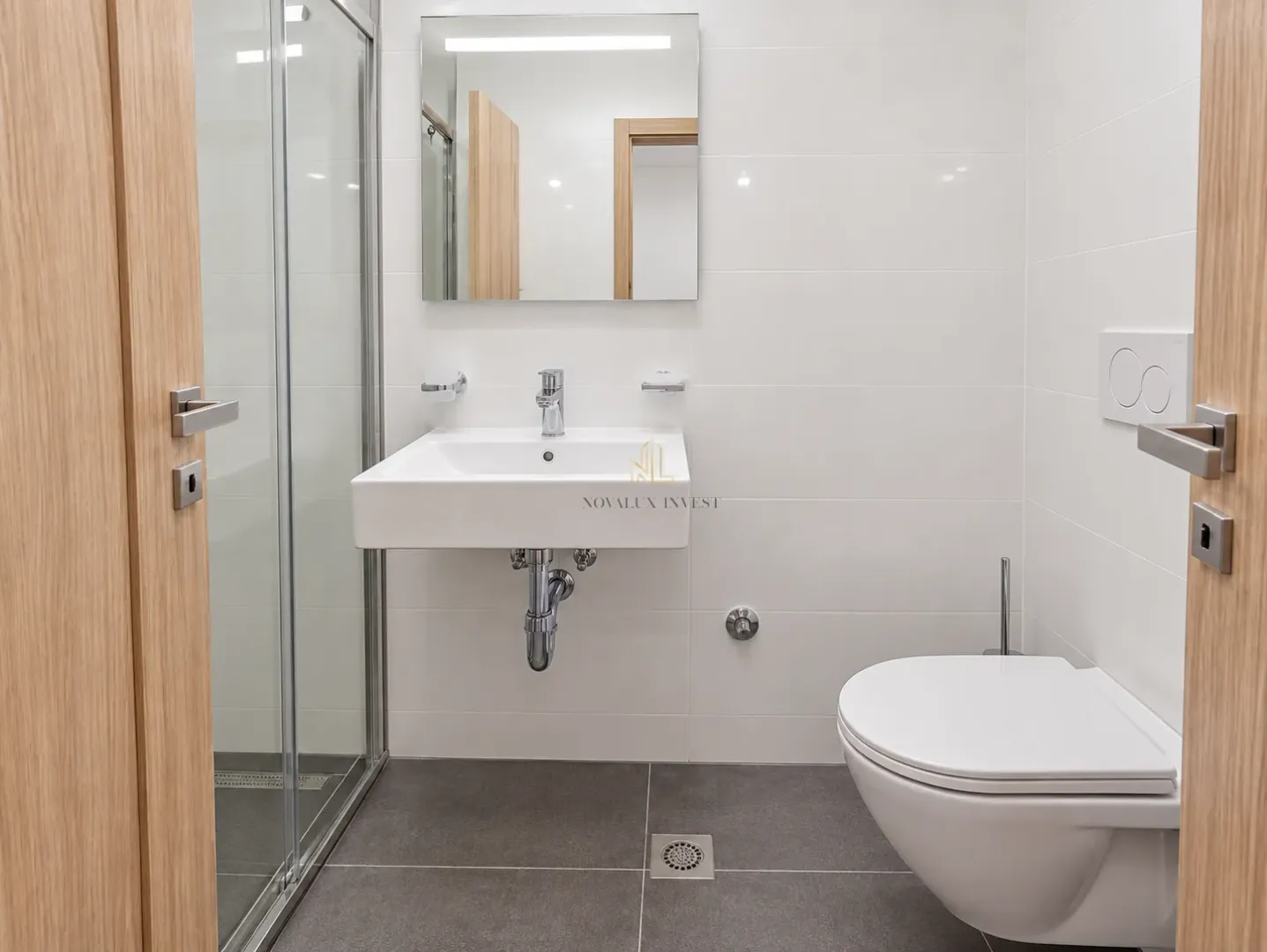 Modern bathroom with a shower cabin, washbasin, and toilet.