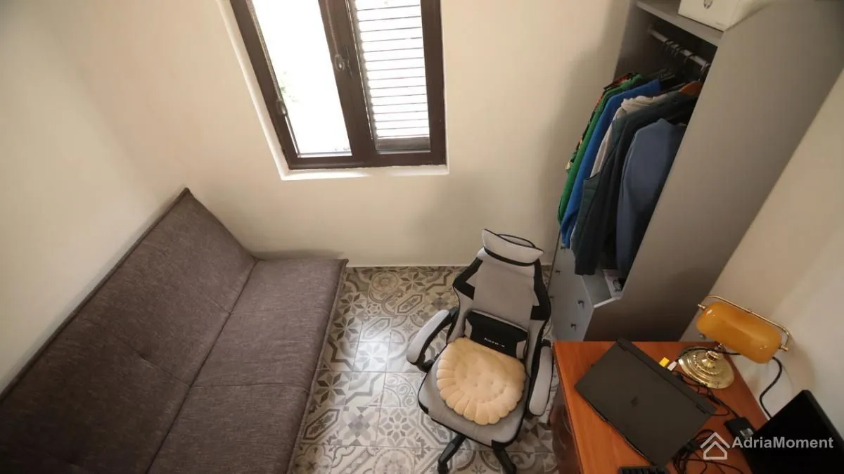 Manja soba sa kaučem na razvlačenje, radnim stolom i ormarom.