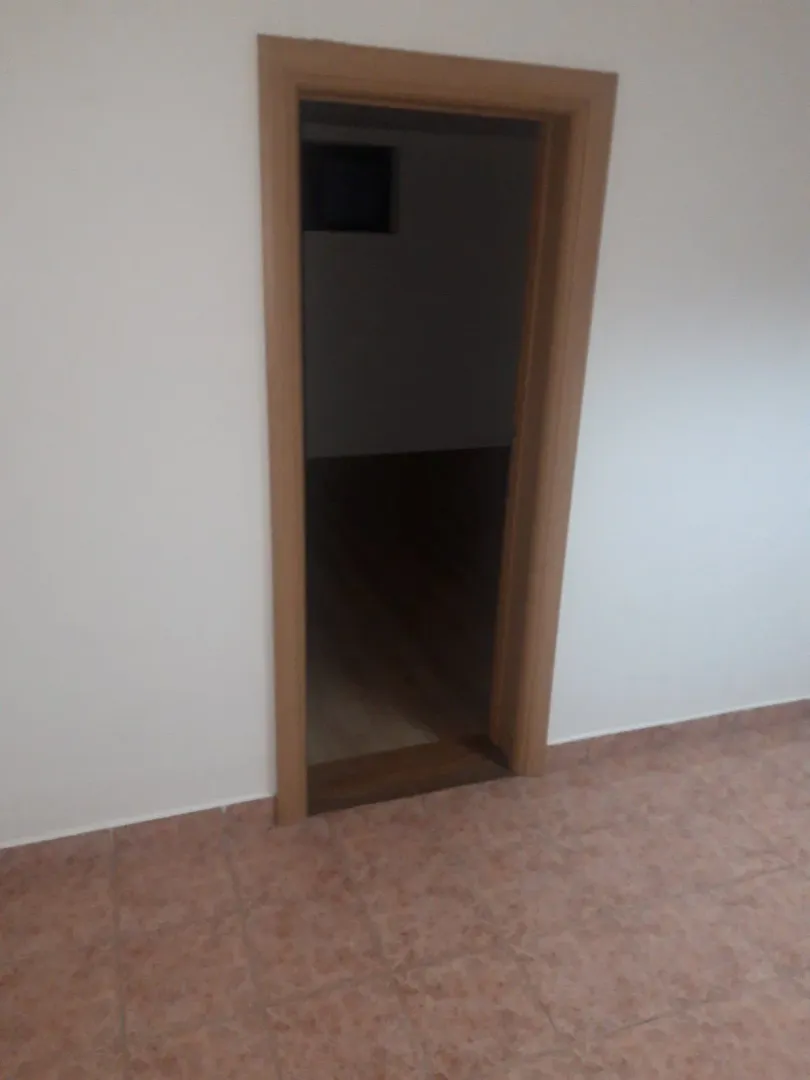 A view through an open wooden door into another room.