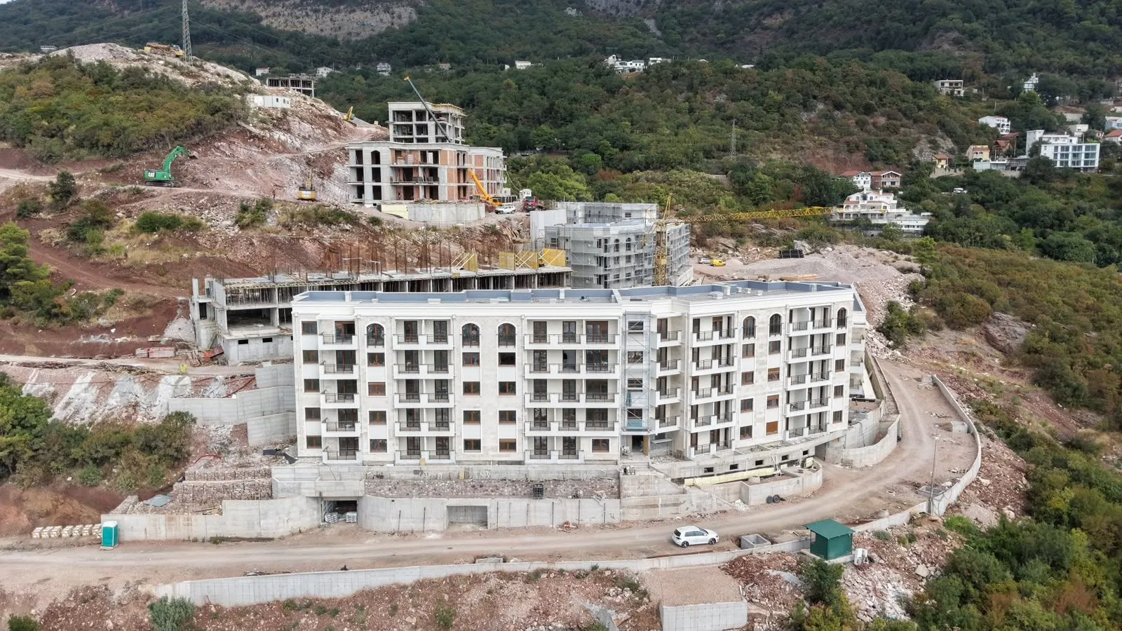 Pogled iz vazduha na stambeni objekat u izgradnji okružen zelenilom.