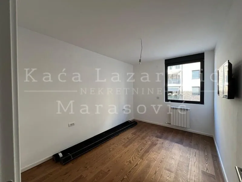 Prazna soba sa drvenim podom i prozorom.