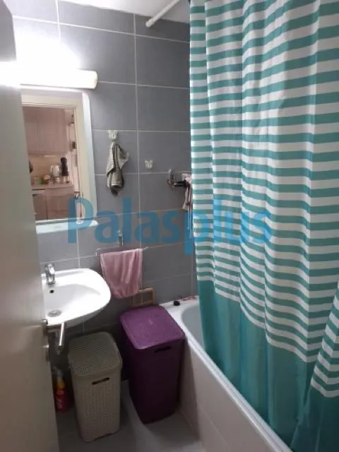 Kupatilo opremljeno tuš kabinom, umivaonikom i korpama za veš.