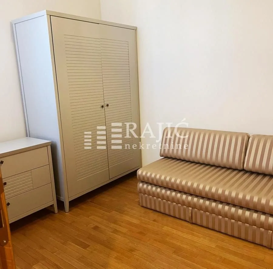 Furnished bedroom with a wardrobe and a sofa.