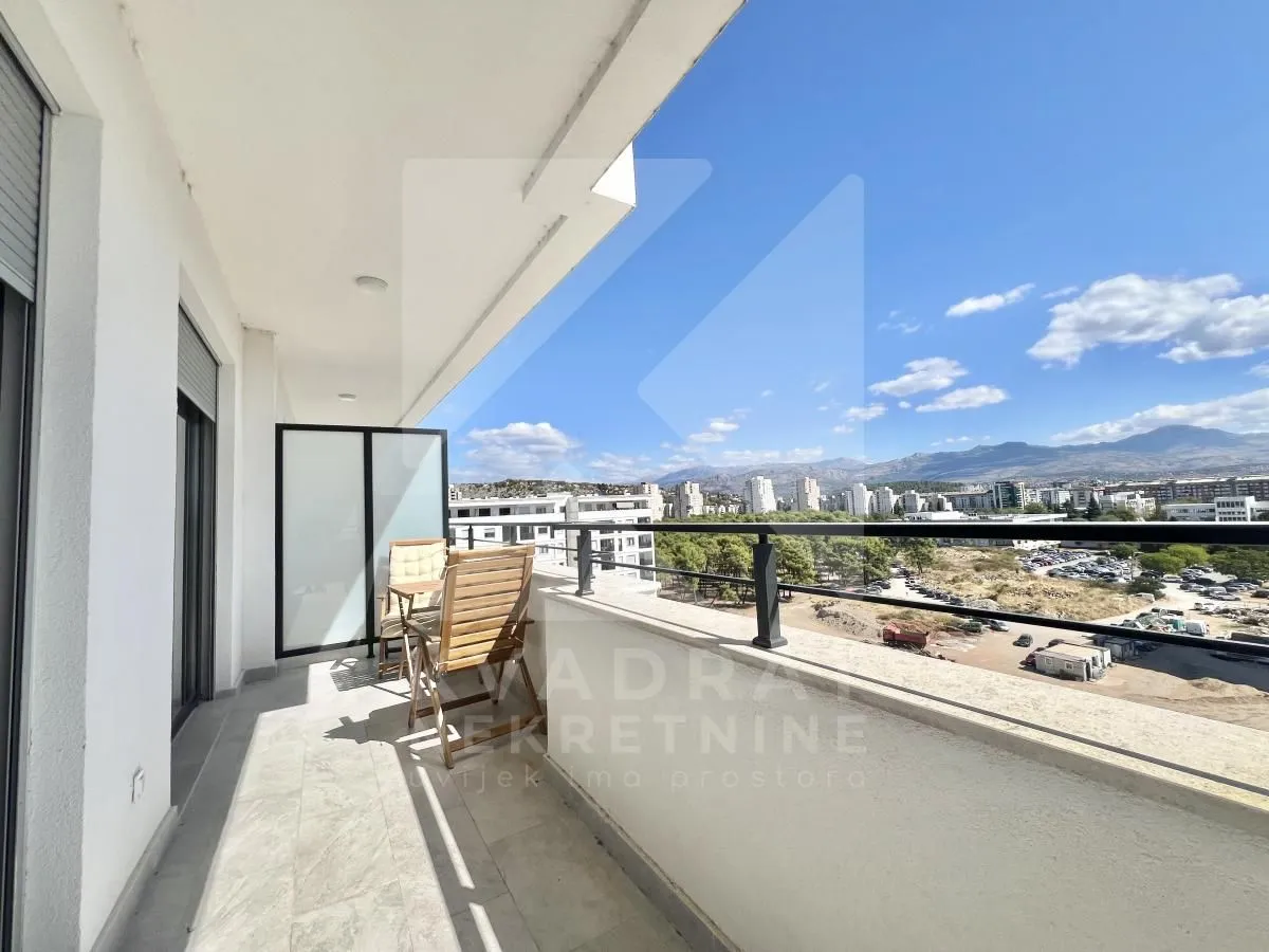 Spacious balcony with seating furniture and a city view.