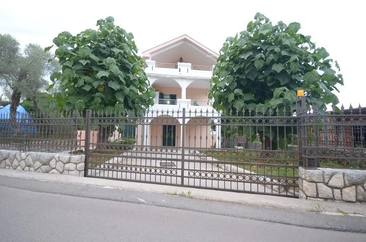 Vanjski izgled trospratne kuće sa ograđenim dvorištem.