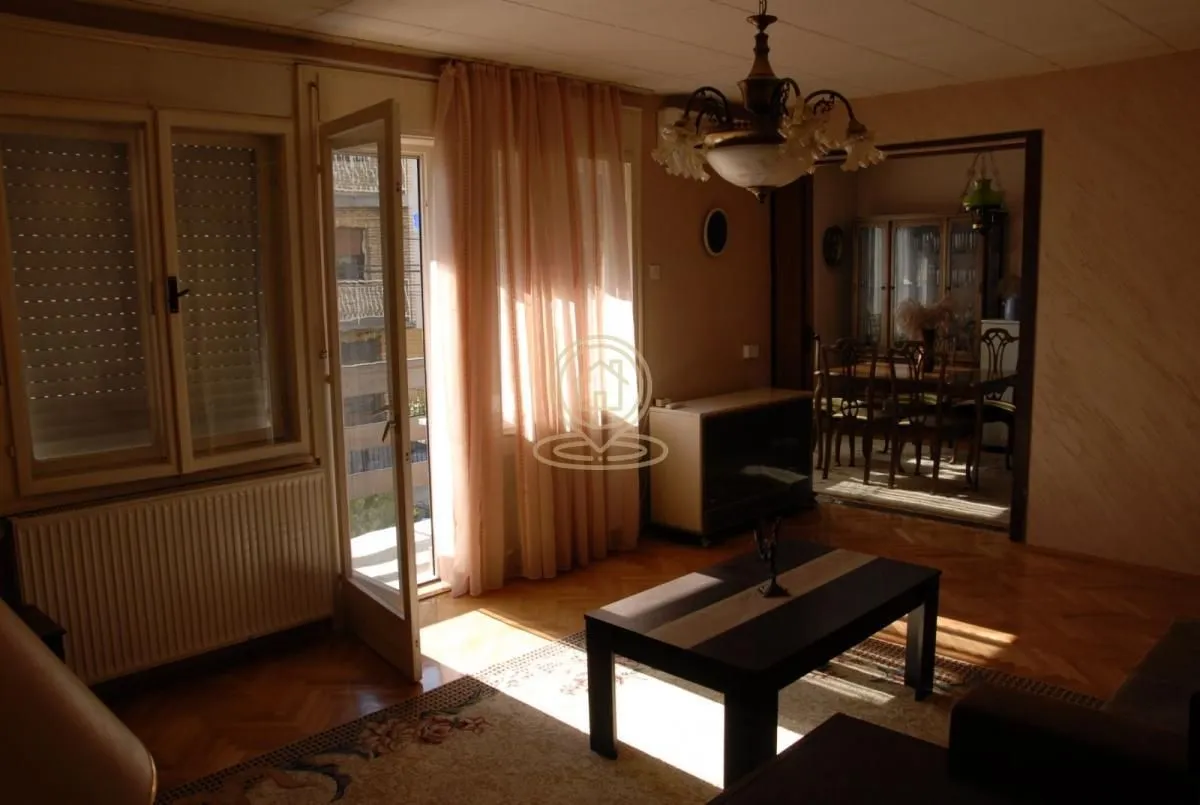 Dnevna soba sa izlazom na terasu i pogledom na susedne zgrade.