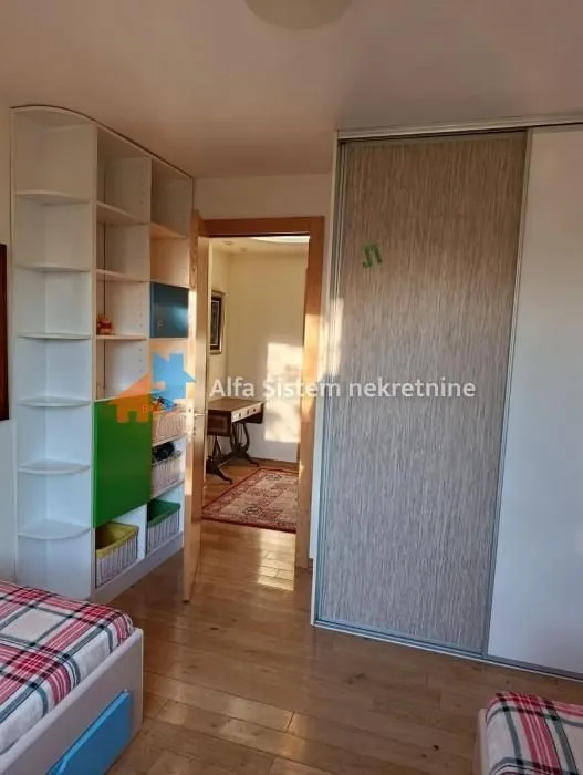 Dečja soba sa krevetima, ugrađenim plakarom i policama.