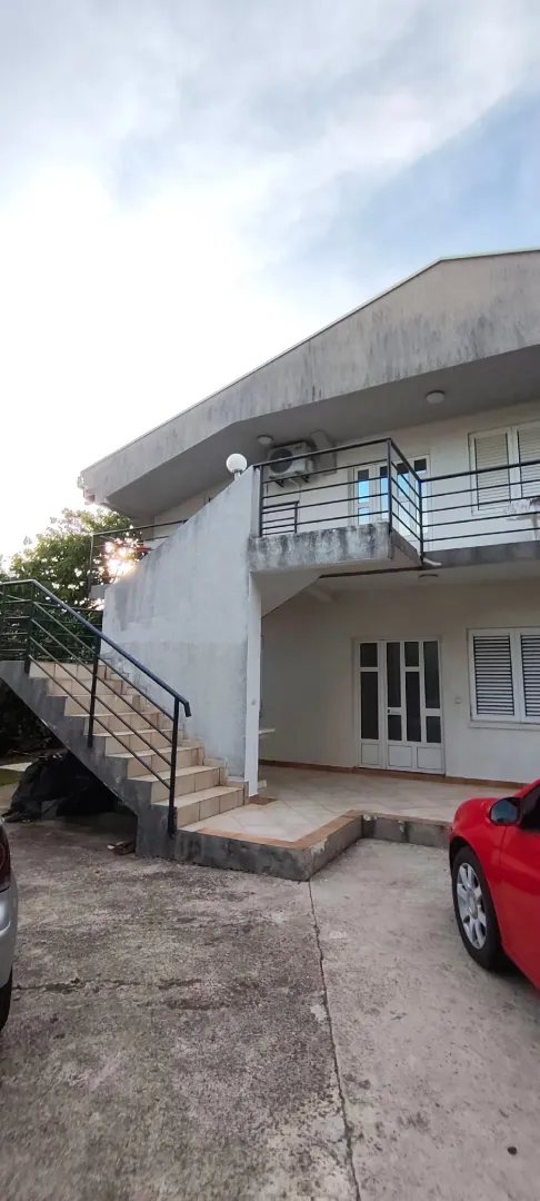 Exterior view of the house with stairs and a yard.