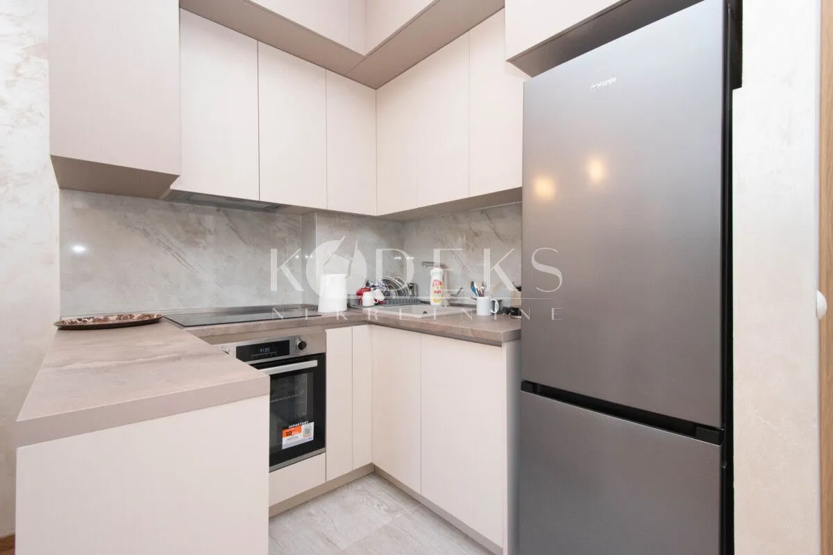 Compact kitchen with light cabinets and built-in appliances.