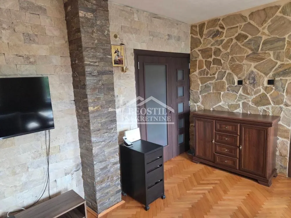 Dnevna soba sa zidovima obloženim kamenom i drvenim nameštajem.