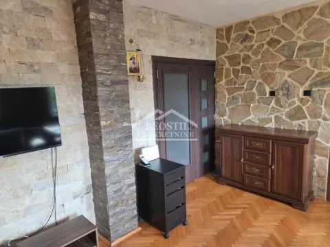 Dnevna soba sa zidovima obloženim kamenom i drvenim nameštajem. - image 16