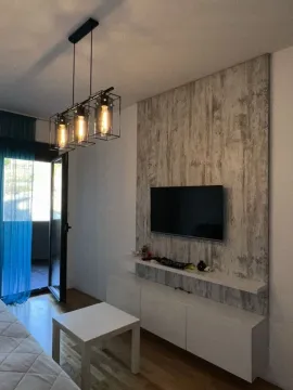 Dnevna soba sa TV-om, bijelim komadom namještaja i modernim visećim lusterom. - image 3