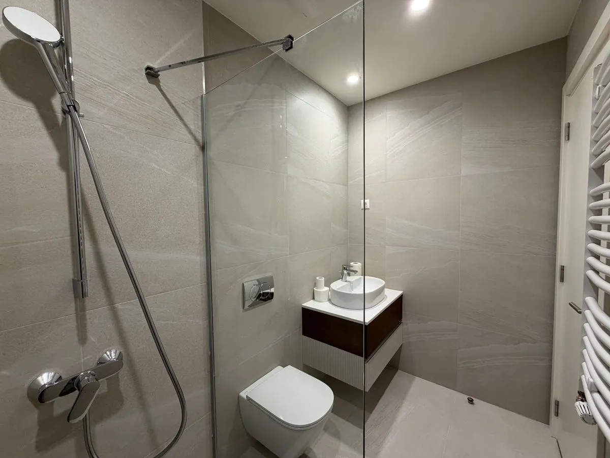Moderno kupatilo sa tuš kabinom, umivaonikom i ugradnom wc šoljom.