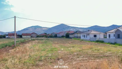 Pogled na plac sa travnatom površinom i okolnim kućama u pozadini. - image 4