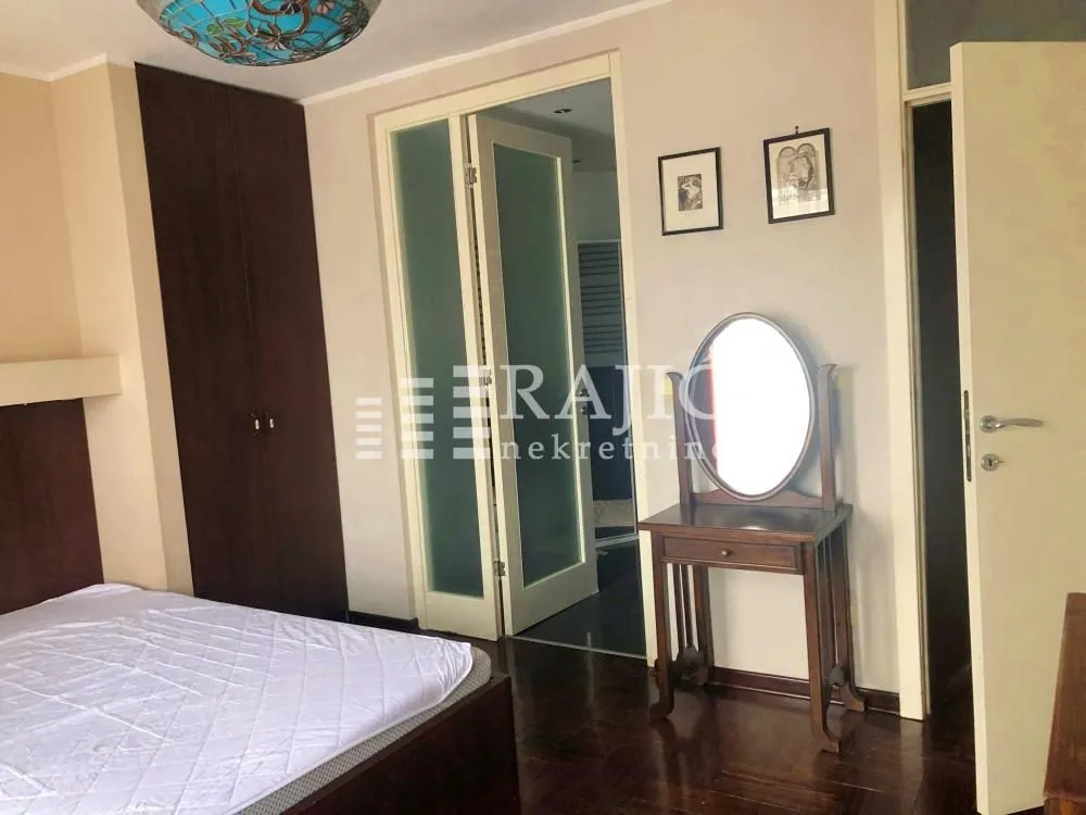 Furnished bedroom with a double bed, wardrobe, and a wooden dressing table.