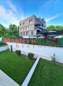 Pogled na zgradu i uređeno dvorište sa travnjakom ispred objekta. - image 4