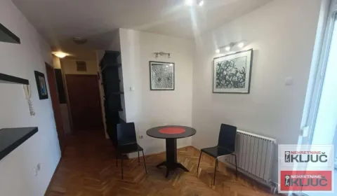 Manja trpezarija sa okruglim stolom i crnim stolicama u stanu. - image 2