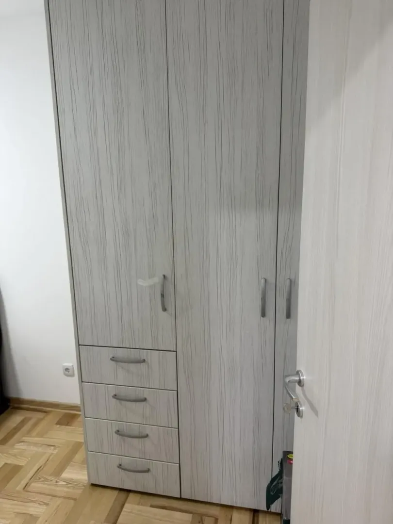 Pogled na veliki drveni garderober u sobi sa parketom.