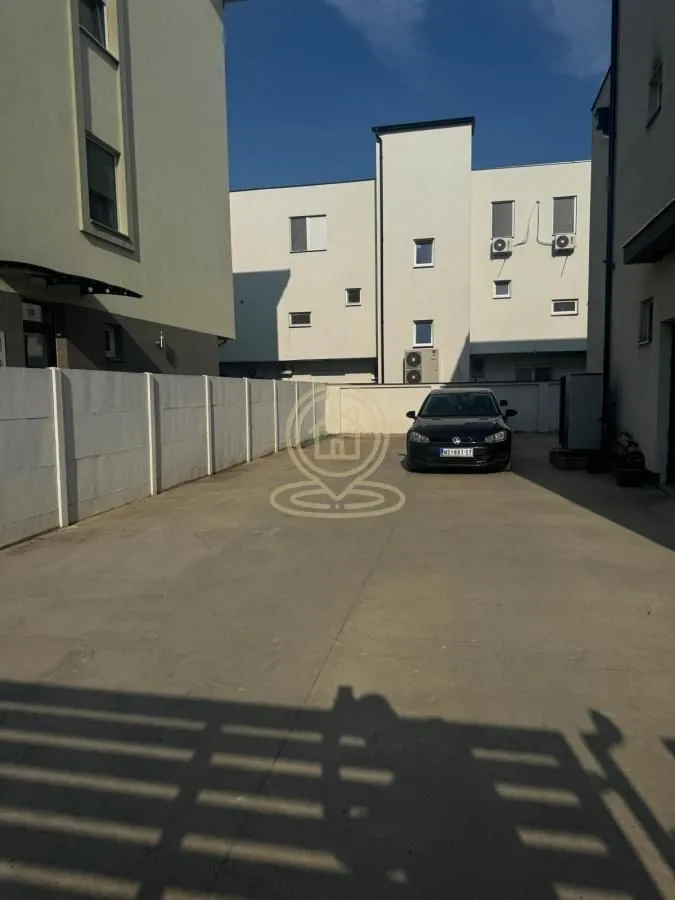 Dvorište sa parking prostorom ispred stambene zgrade.