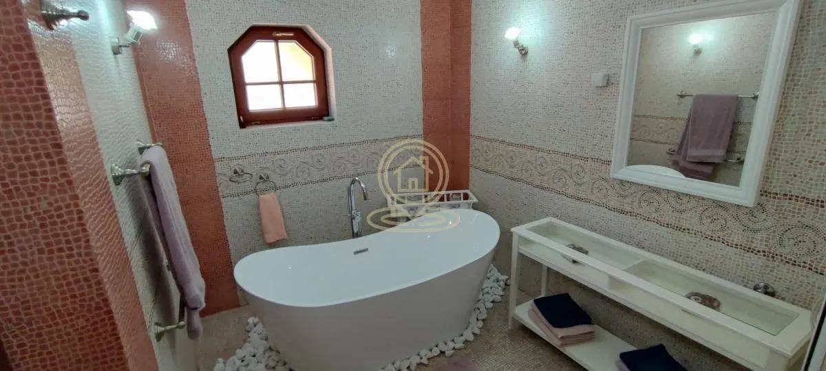 Bathroom with a freestanding bathtub, washbasin, and decorative mosaic tiles.