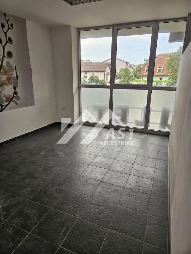 Empty room with dark floor tiles and a large window.