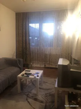 Dnevna soba sa garniturom, stočićem i televizorom pored prozora sa zavesama. - image 3