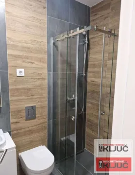 Savremeno opremljeno kupatilo sa tuš kabinom i keramičkim pločicama u imitaciji drveta. - image 6