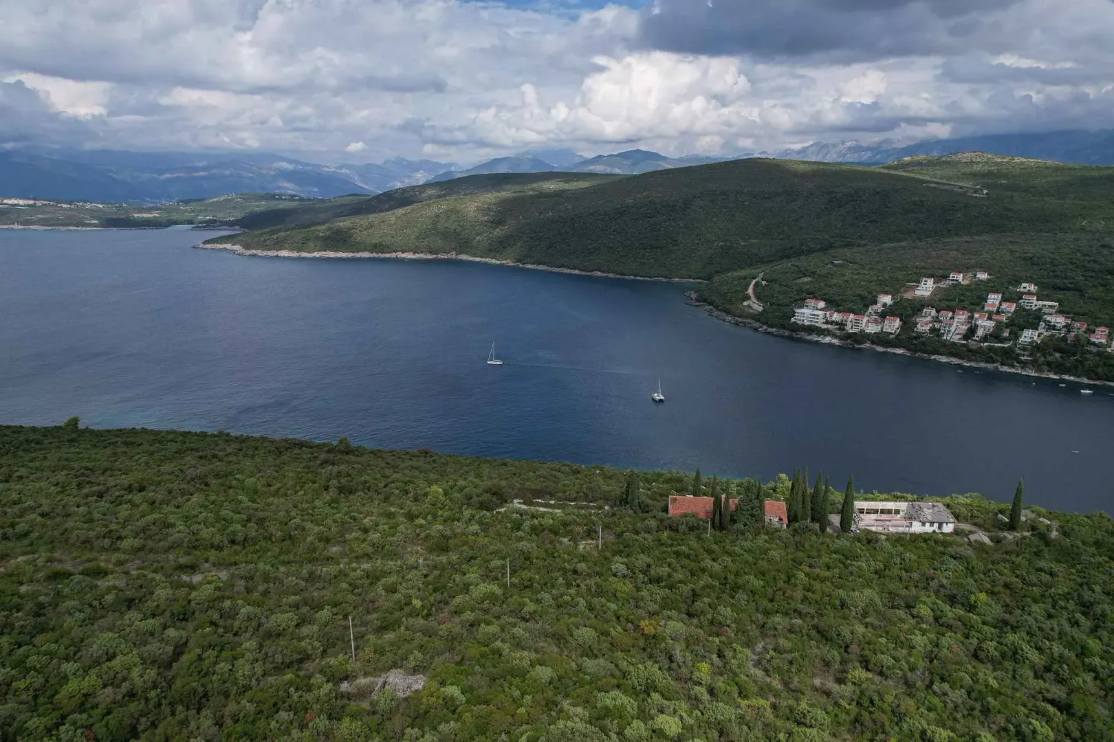 Pogled iz vazduha na zaliv, okolna brda i obalu sa jedrilicama.