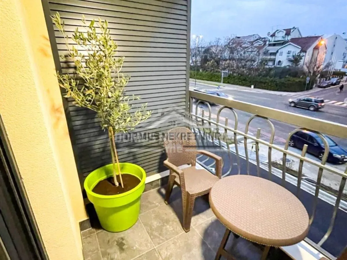 Manji namješteni balkon sa stolom, stolicom i ukrasnom biljkom.