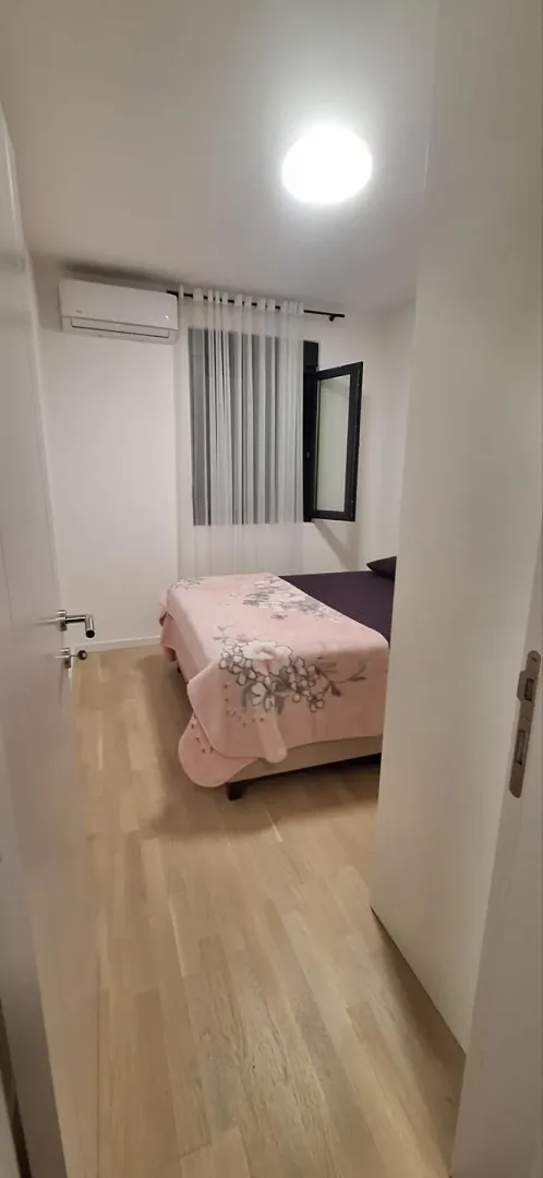 Manja spavaća soba sa bračnim krevetom i svijetlim enterijerom.